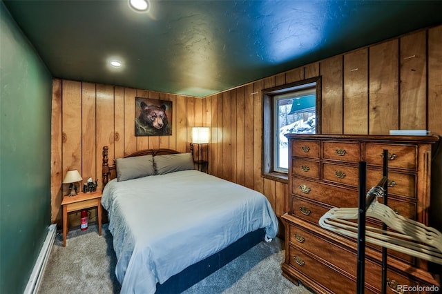 carpeted bedroom featuring wood walls and a baseboard heating unit