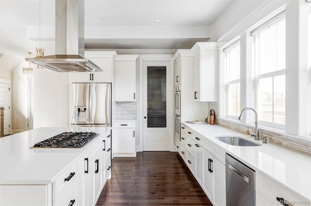 kitchen with appliances with stainless steel finishes, island range hood, white cabinetry, and sink