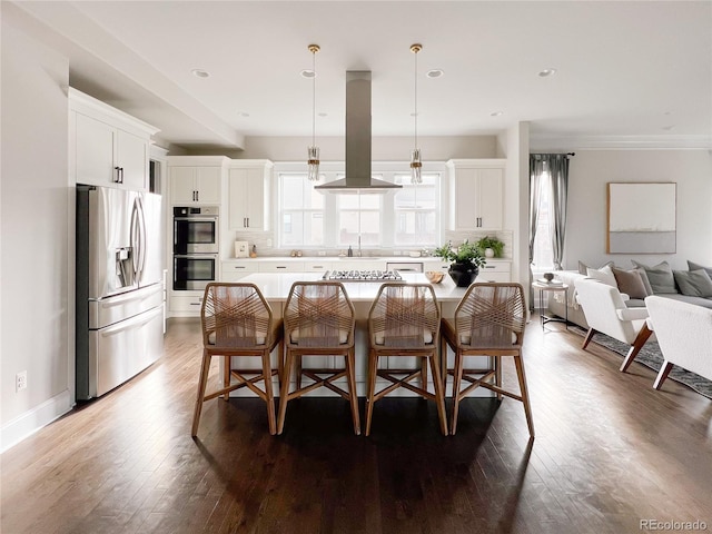 kitchen with pendant lighting, a kitchen island, island range hood, white cabinetry, and stainless steel appliances