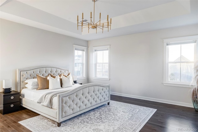 bedroom featuring a tray ceiling, dark hardwood / wood-style floors, and a notable chandelier