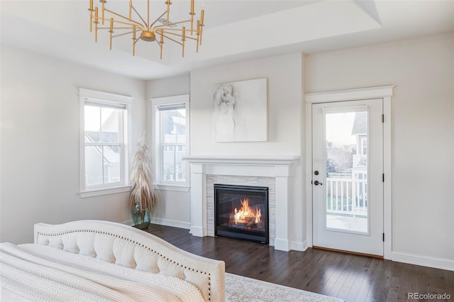 bedroom with access to exterior, a fireplace, a raised ceiling, dark wood-type flooring, and a chandelier