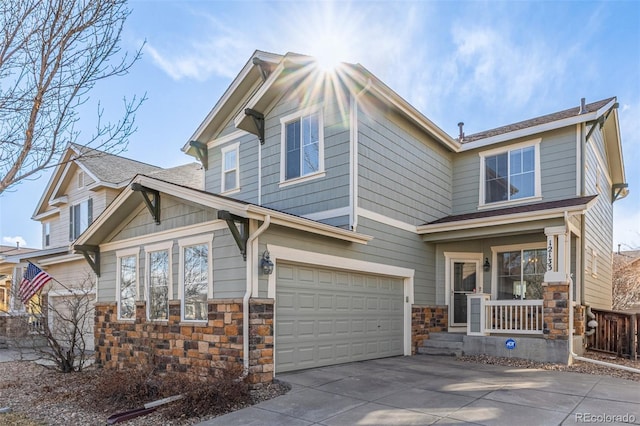 view of front of home with concrete driveway, stone siding, an attached garage, covered porch, and fence