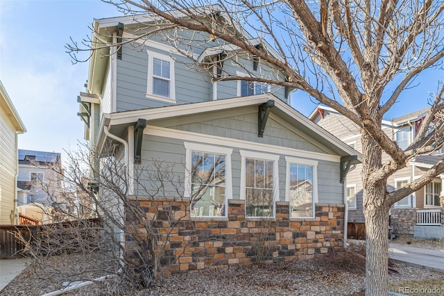 view of side of property featuring stone siding and fence