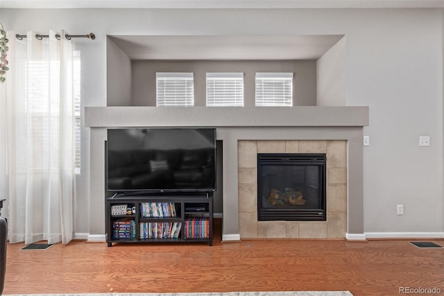 details featuring baseboards, a fireplace, visible vents, and wood finished floors