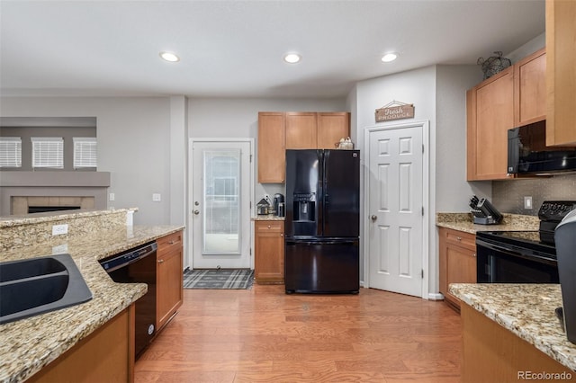 kitchen featuring light wood-style floors, light stone counters, black appliances, a sink, and recessed lighting