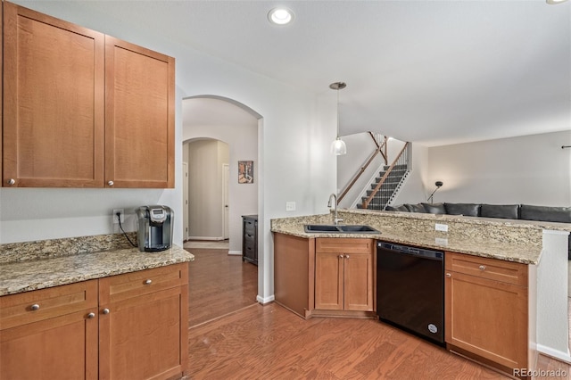 kitchen featuring black dishwasher, open floor plan, a sink, light wood-type flooring, and a peninsula