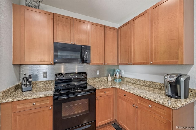 kitchen with black appliances, light stone counters, and backsplash