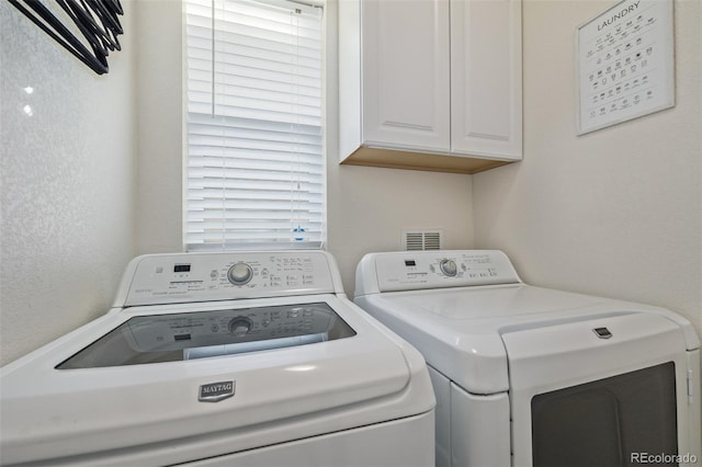 laundry room with a textured wall, washer and clothes dryer, and cabinet space