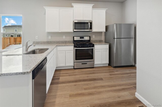 2165 Alyssa St, Fort Lupton, CO 80621 - kitchen with appliances with stainless steel finishes, a sink, white cabinets, a peninsula, and light stone counters