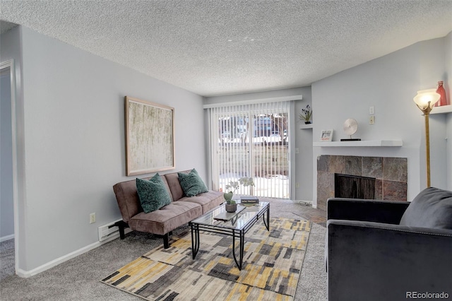 living room featuring a tiled fireplace, baseboard heating, carpet, and a textured ceiling