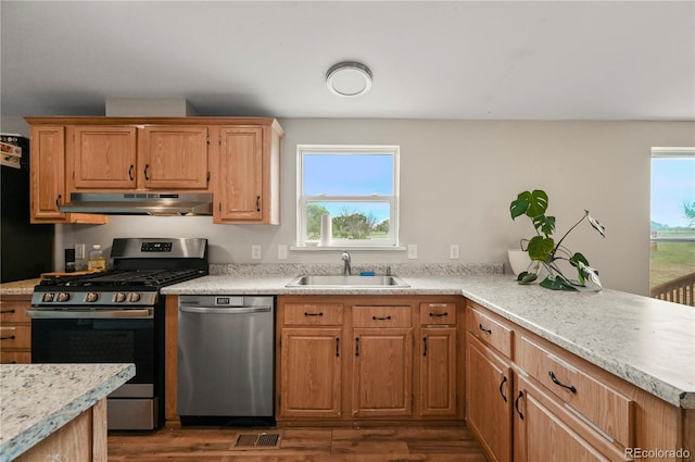5520 Coyote Ln, Peyton, CO 80831 - kitchen with appliances with stainless steel finishes, under cabinet range hood, dark wood-type flooring, and plenty of natural light