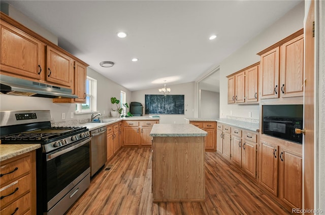 5520 Coyote Ln, Peyton, CO 80831 - kitchen featuring stainless steel appliances, under cabinet range hood, wood finished floors, light countertops, and vaulted ceiling