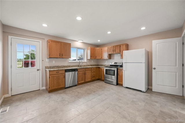 5520 Coyote Ln, Peyton, CO 80831 - kitchen featuring stainless steel appliances, recessed lighting, light stone counters, brown cabinetry, and light tile patterned flooring