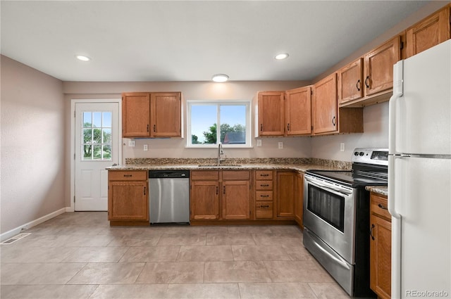 5520 Coyote Ln, Peyton, CO 80831 - kitchen with appliances with stainless steel finishes, recessed lighting, brown cabinets, light stone countertops, and light tile patterned floors