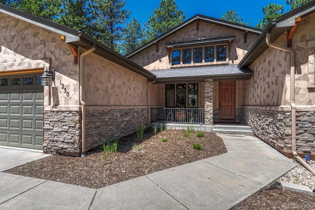 1250 Cottontail Trl, Woodland Park, CO 80863 - doorway to property featuring covered porch, stone siding, stucco siding, and a garage