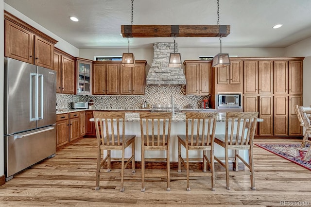 1250 Cottontail Trl, Woodland Park, CO 80863 - kitchen with appliances with stainless steel finishes, light wood-style flooring, custom range hood, brown cabinetry, and recessed lighting