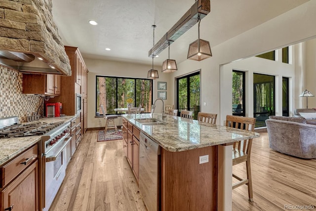 1250 Cottontail Trl, Woodland Park, CO 80863 - kitchen with appliances with stainless steel finishes, wall chimney range hood, a kitchen bar, brown cabinetry, and decorative backsplash