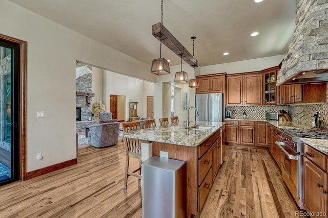 1250 Cottontail Trl, Woodland Park, CO 80863 - kitchen featuring stainless steel appliances, custom range hood, brown cabinetry, light wood-style floors, and light stone countertops