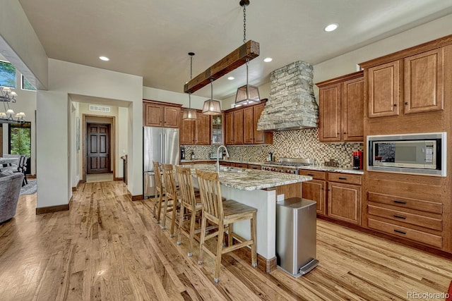 1250 Cottontail Trl, Woodland Park, CO 80863 - kitchen with appliances with stainless steel finishes, brown cabinets, custom range hood, light wood finished floors, and recessed lighting
