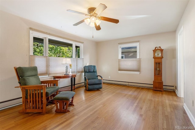 living area with a baseboard radiator, light hardwood / wood-style flooring, and ceiling fan