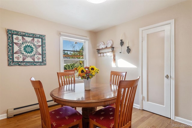 dining space with light hardwood / wood-style floors and a baseboard heating unit