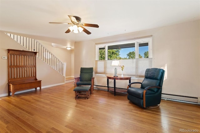 sitting room with ceiling fan, a baseboard heating unit, and light hardwood / wood-style floors