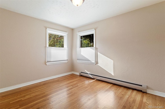 unfurnished room with hardwood / wood-style floors and a baseboard radiator