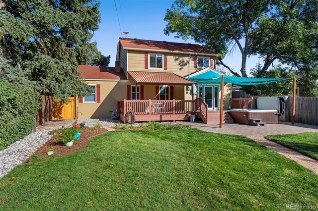 rear view of house featuring a deck, a hot tub, a lawn, and a patio