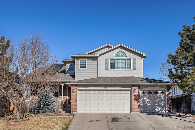 traditional home featuring roof with shingles, fence, concrete driveway, and brick siding