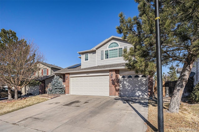 traditional-style home with an attached garage, roof mounted solar panels, concrete driveway, and brick siding