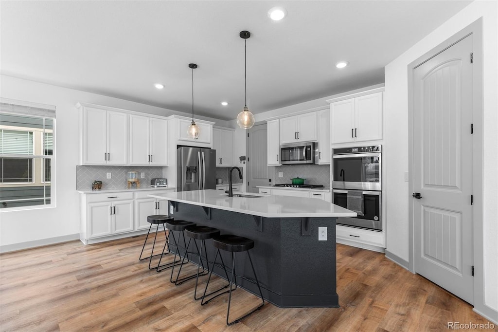 kitchen featuring white cabinetry, stainless steel appliances, sink, and an island with sink