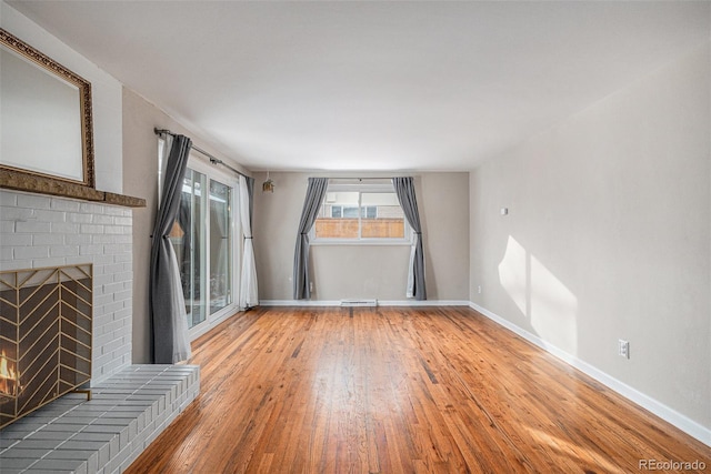 unfurnished living room featuring a brick fireplace and hardwood / wood-style flooring