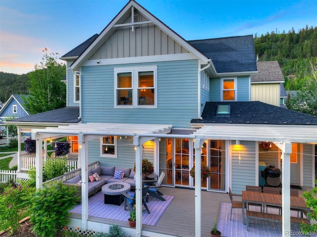 17 Meadow Lark Grn, Breckenridge, CO 80424 - back of property at dusk with a wooden deck, board and batten siding, an outdoor living space with a fire pit, a shingled roof, and outdoor dining space