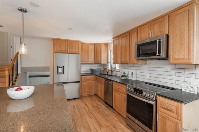 8170 S Marshall Ct, Littleton, CO 80128 - kitchen with decorative backsplash, appliances with stainless steel finishes, hanging light fixtures, a sink, and light wood-style floors