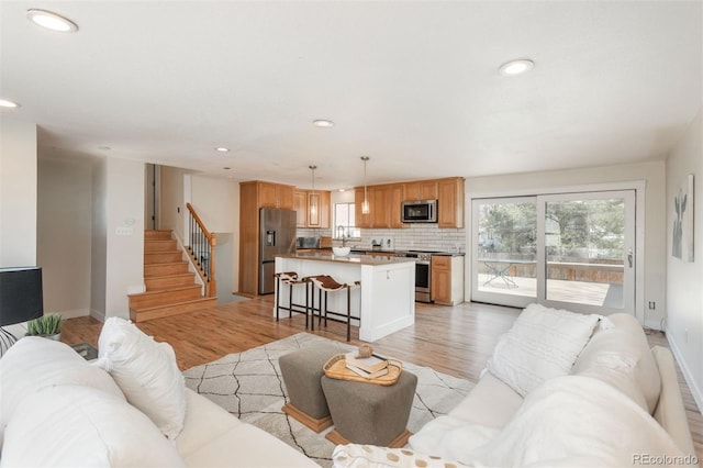 8170 S Marshall Ct, Littleton, CO 80128 - living area featuring recessed lighting, light wood finished floors, baseboards, and stairway