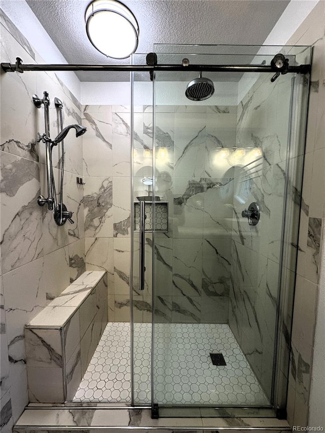 full bath featuring a marble finish shower and a textured ceiling