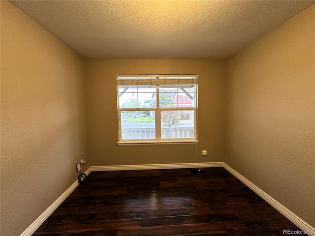 empty room with dark wood-style flooring, baseboards, and a textured ceiling