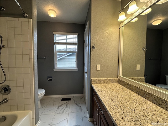 bathroom featuring toilet, marble finish floors, vanity, shower / bath combination, and baseboards