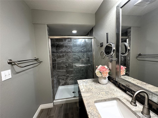 full bath with wood finished floors, a stall shower, vanity, and baseboards