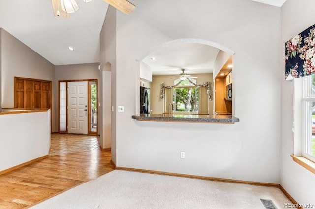 entryway with visible vents, wood finished floors, arched walkways, baseboards, and vaulted ceiling