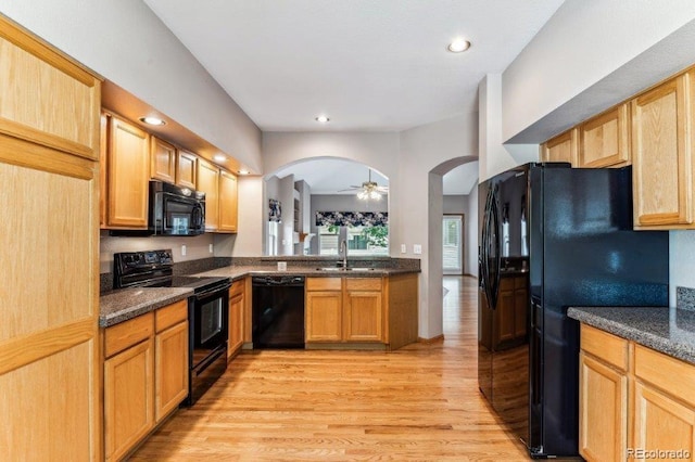 kitchen with black appliances, a sink, recessed lighting, arched walkways, and light wood-style floors