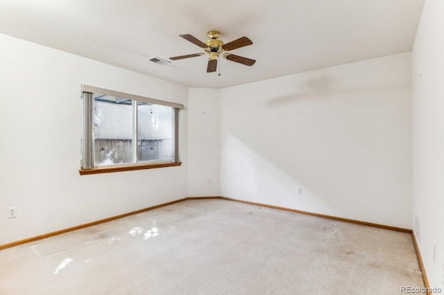 carpeted empty room featuring a textured ceiling, baseboards, visible vents, and ceiling fan