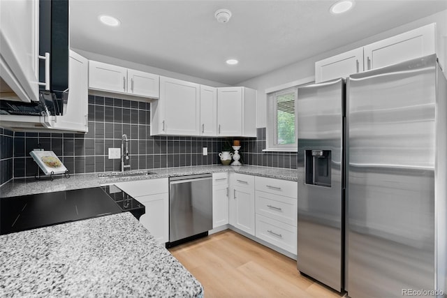 8333 Depew Way, Arvada, CO 80003 - kitchen with appliances with stainless steel finishes, a sink, white cabinets, light stone counters, and tasteful backsplash