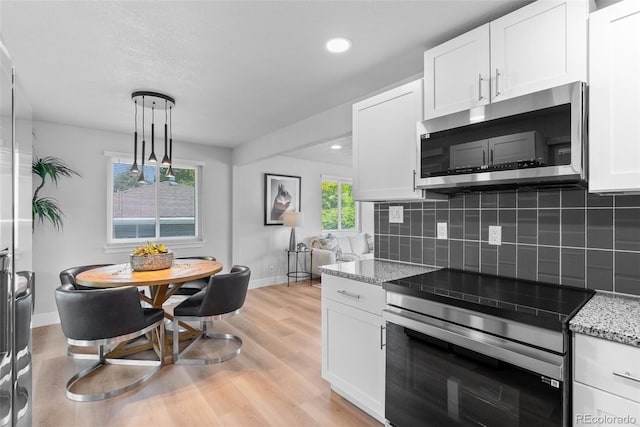 8333 Depew Way, Arvada, CO 80003 - kitchen featuring appliances with stainless steel finishes, decorative backsplash, white cabinetry, light wood-style floors, and baseboards