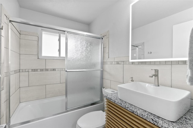 8333 Depew Way, Arvada, CO 80003 - full bathroom featuring toilet, vanity, tile walls, and combined bath / shower with glass door