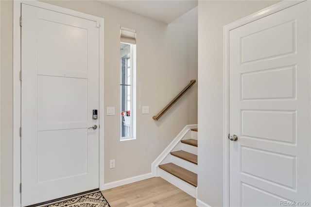 foyer entrance featuring stairway, light wood-style flooring, and baseboards