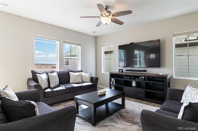 living area featuring visible vents, baseboards, light wood-style floors, and ceiling fan