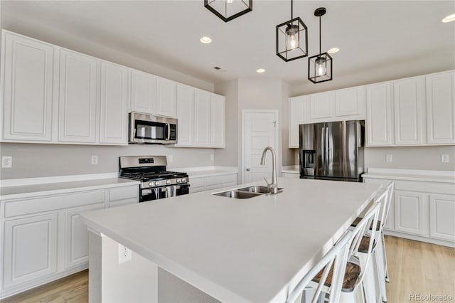 kitchen featuring a center island with sink, recessed lighting, appliances with stainless steel finishes, white cabinetry, and a sink