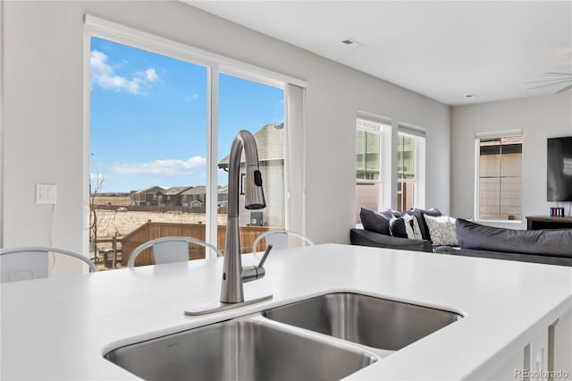 kitchen featuring a sink, visible vents, open floor plan, and light countertops