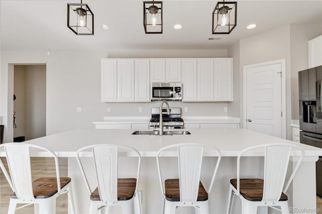 kitchen featuring recessed lighting, stainless steel appliances, light countertops, white cabinetry, and decorative light fixtures